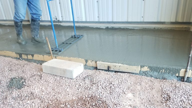 A man is using a tamper on a fresh concrete pour.