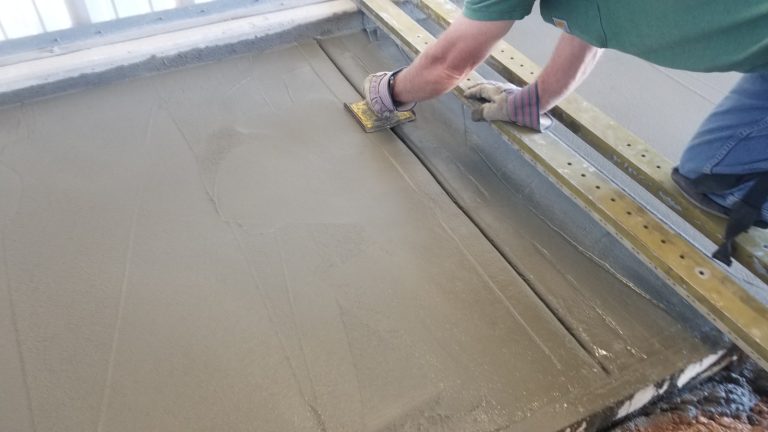 A man using a hand joint tool to work on the joints in the concrete.