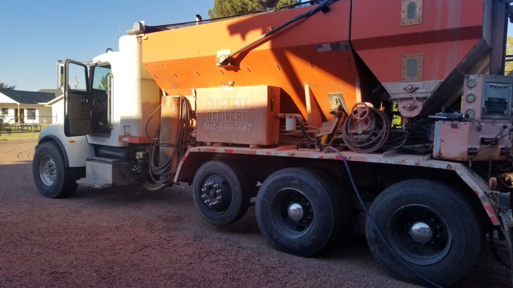 A red and white truck, mobile concrete mixer, driver door is open.