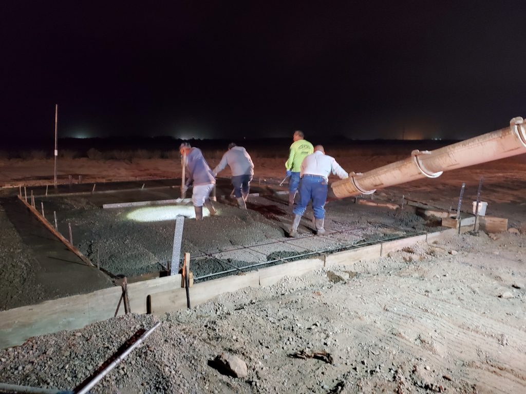 Concrete crew pouring concrete at night time.
