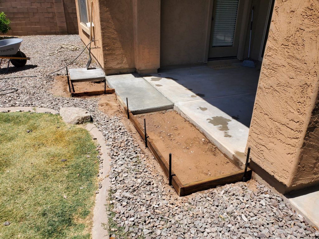 Wooden forms setup to pour concrete to widen a backyard patio.