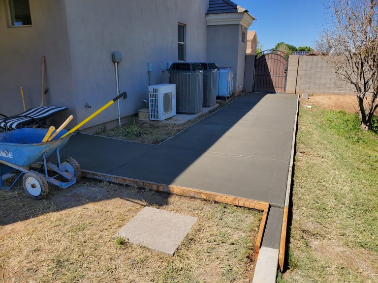 A newly poured concrete sidewalk still inside its forms in the backyard of a residential home in Gilbert, Arizona.