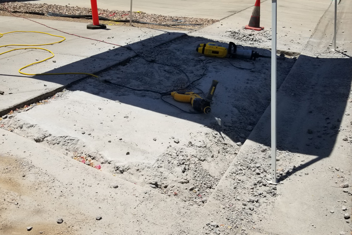 Sidewalk being demolished and broken out with a jackhammer and tools