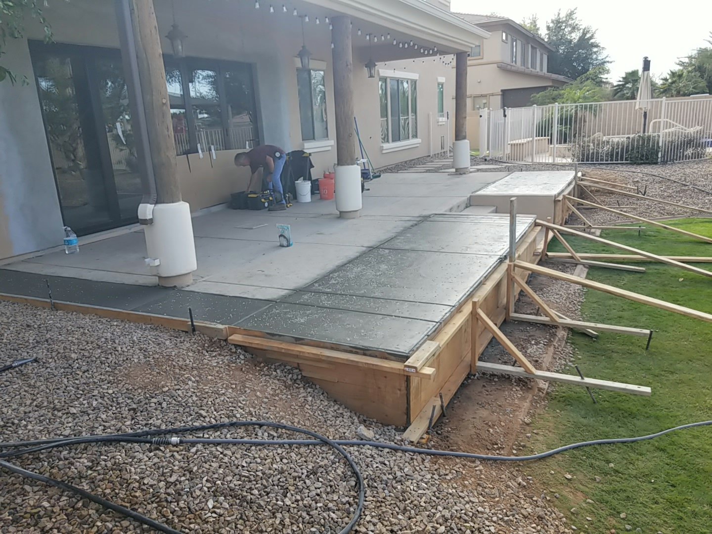 Fresh concrete patio extension held by timber edge forms beside the lawn