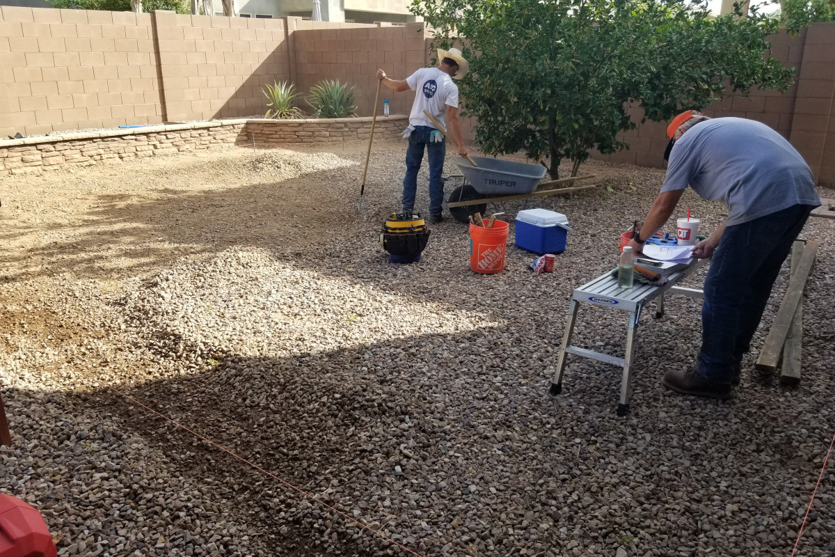 Crew checking grade and layout for a backyard concrete patio project.