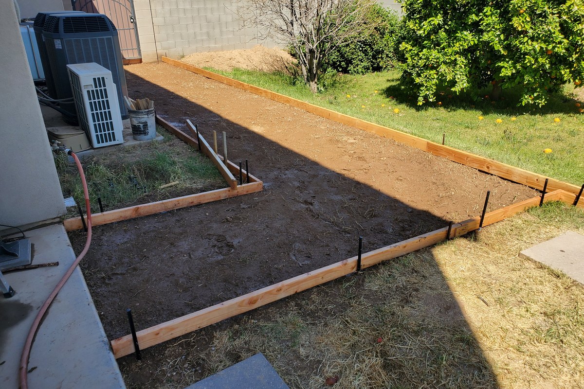 Wide view of the side-yard sidewalk forms leading toward the rear gate.