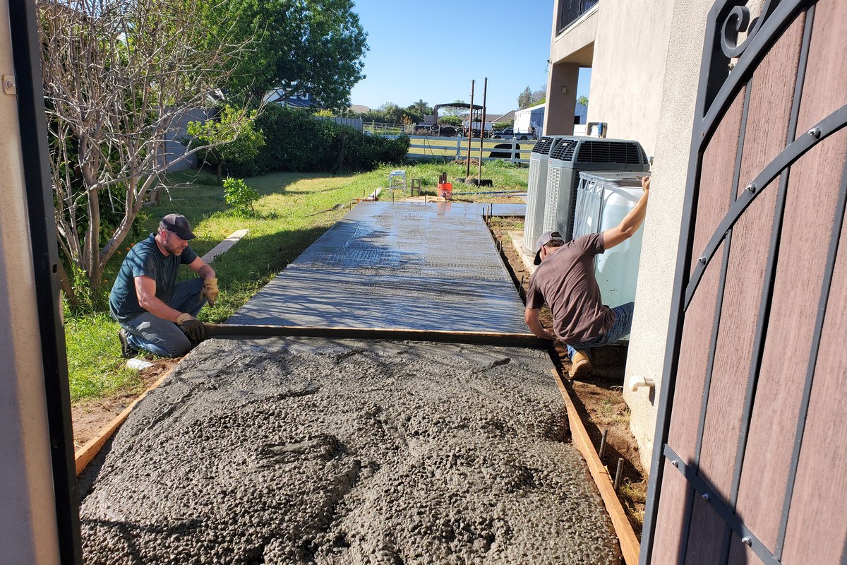 Concrete crew screeding and finishing the new side-yard sidewalk addition in Gilbert, Arizona.