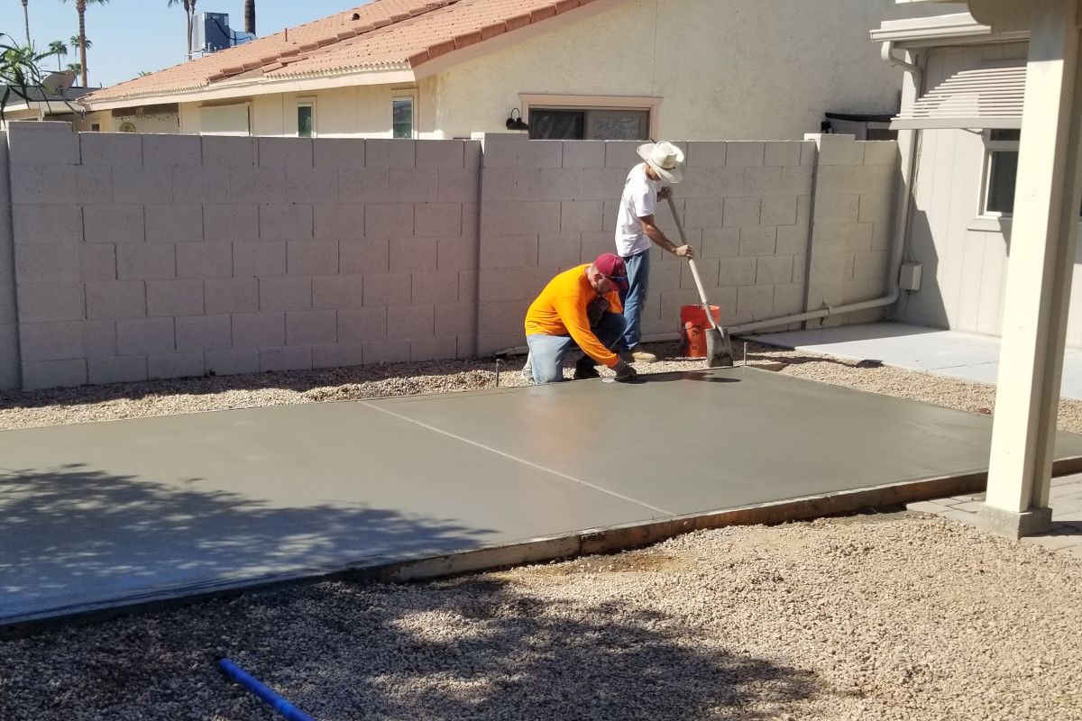 Concrete finish work in progress on a backyard shed slab.