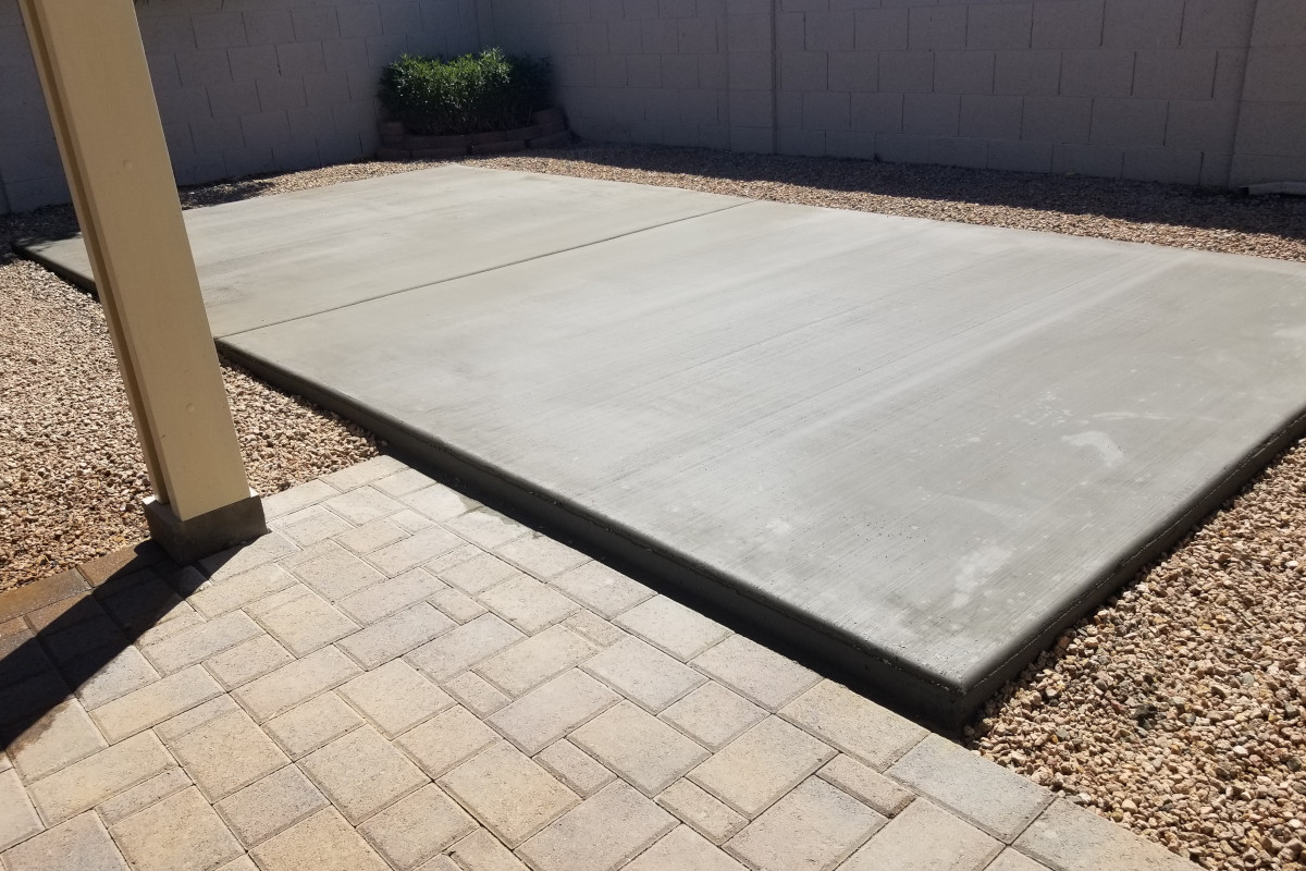 Finished corner view of the backyard shed slab beside an existing patio.
