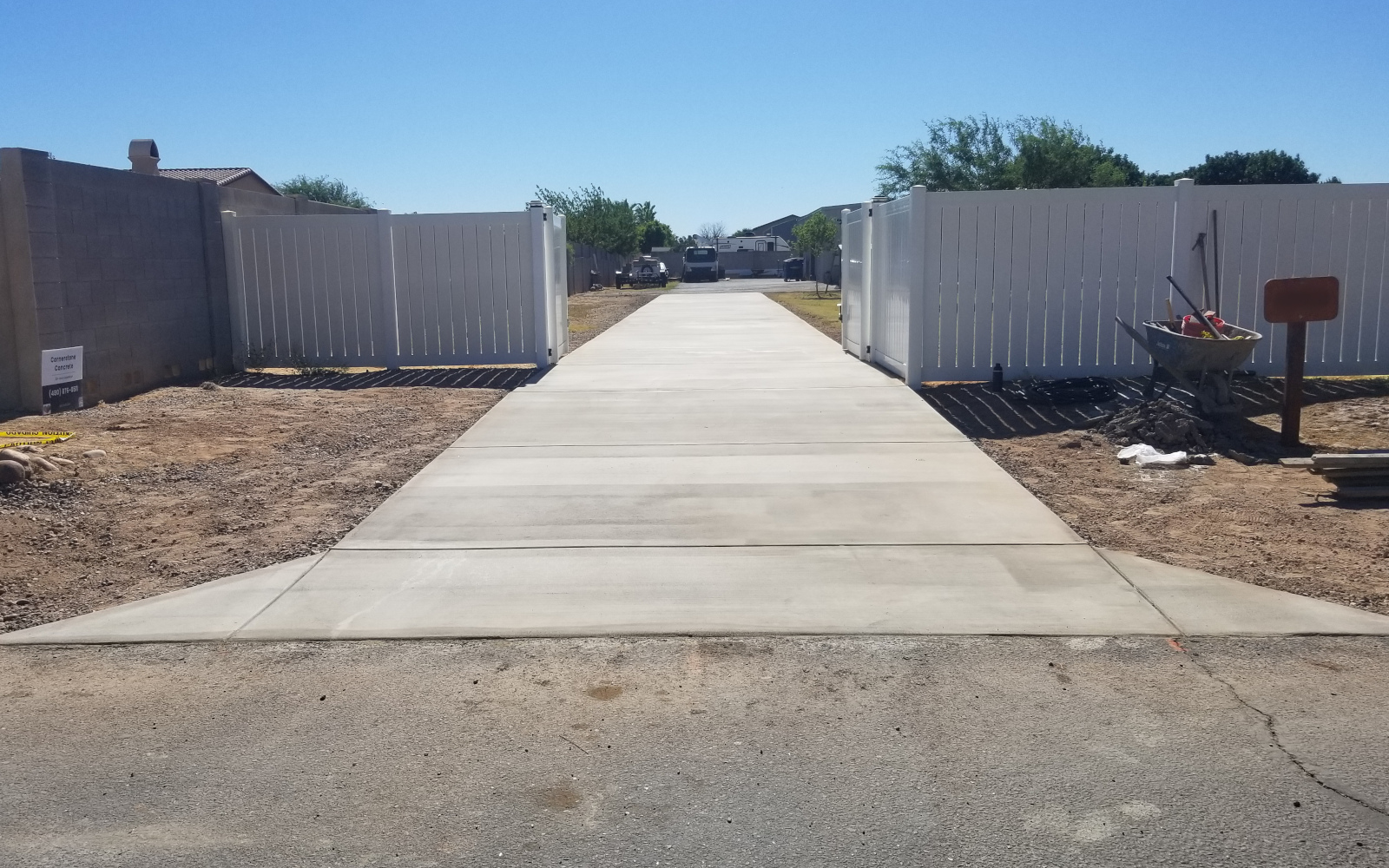Finished 100-foot concrete driveway leading through open gates in Gilbert, Arizona.