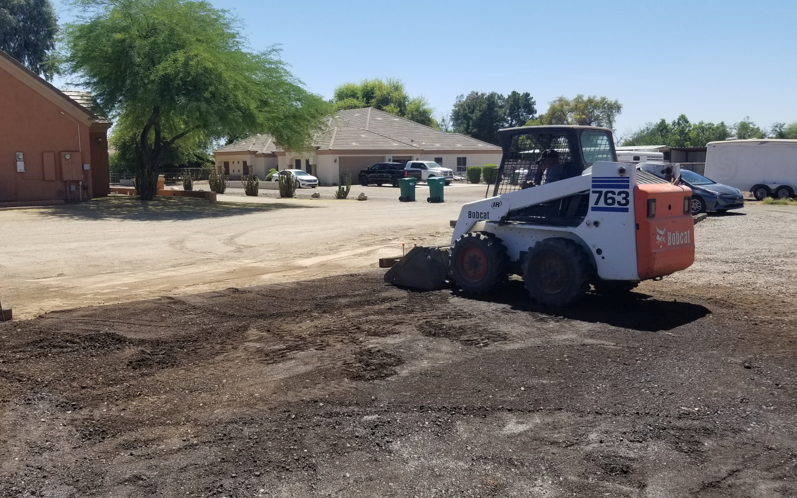 Skid steer grading the prepared base for a Gilbert driveway section