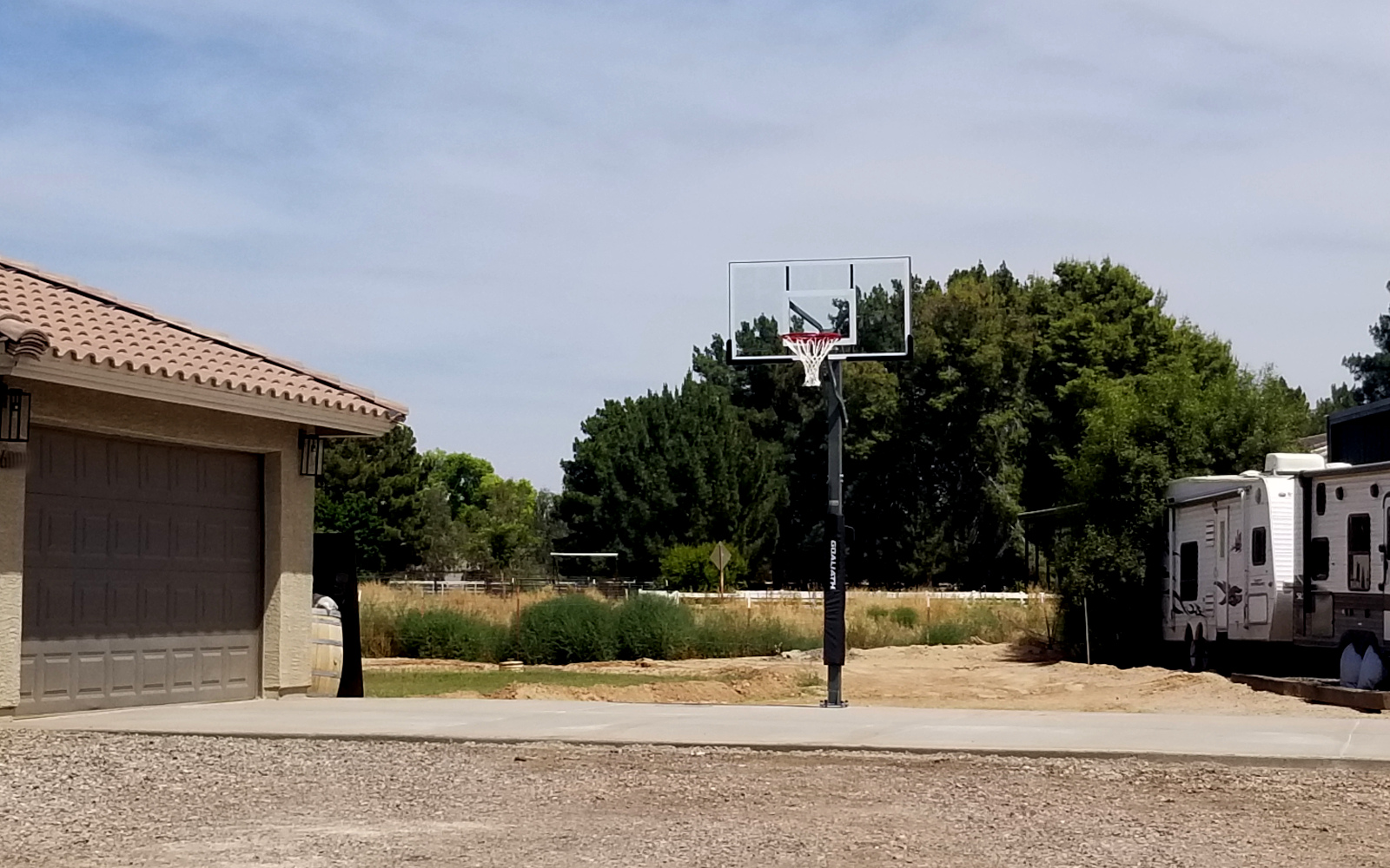 Completed basketball hoop on a new concrete pad beside a Gilbert garage.