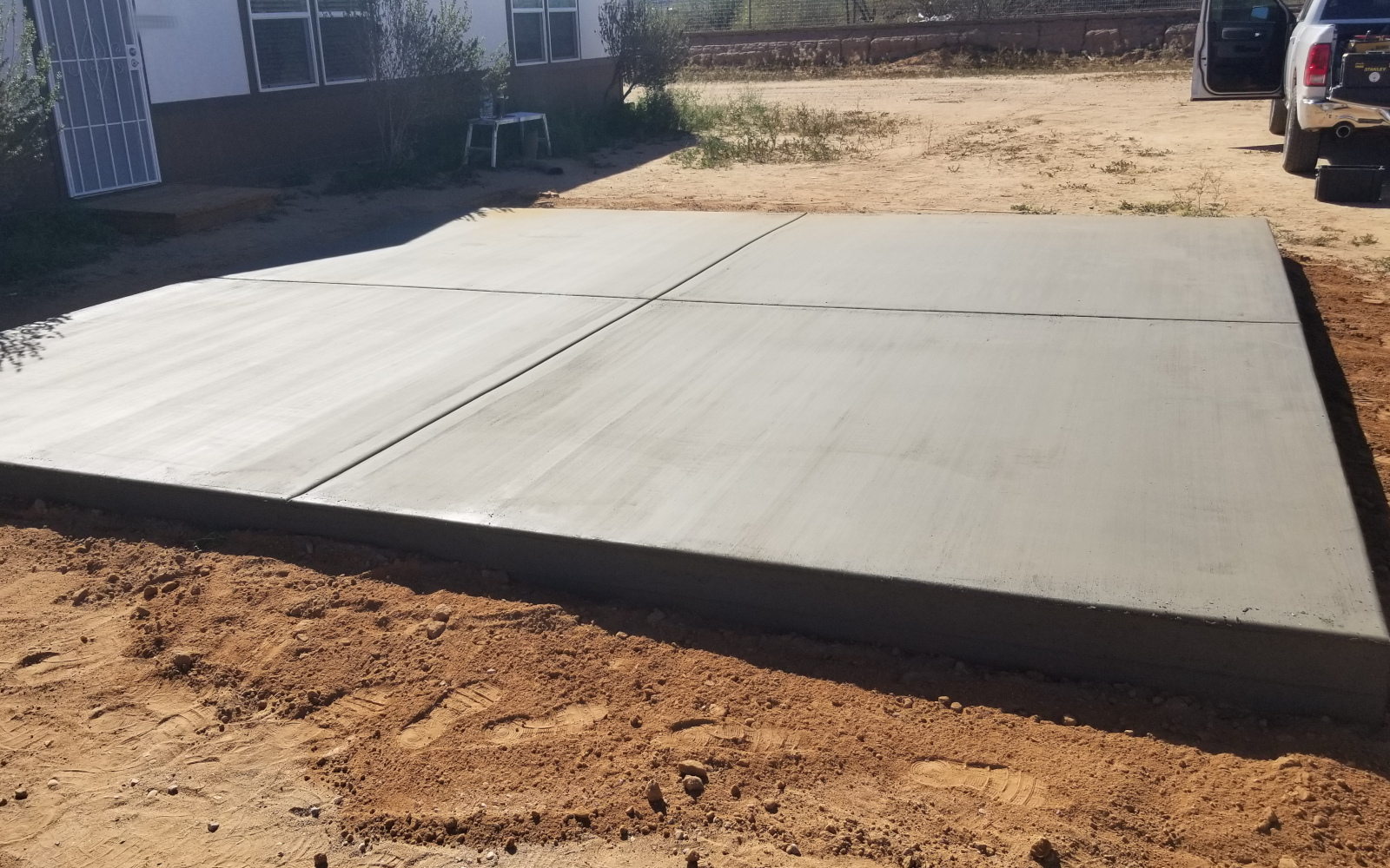 Wide view of a finished reinforced concrete pad beside a Maricopa home