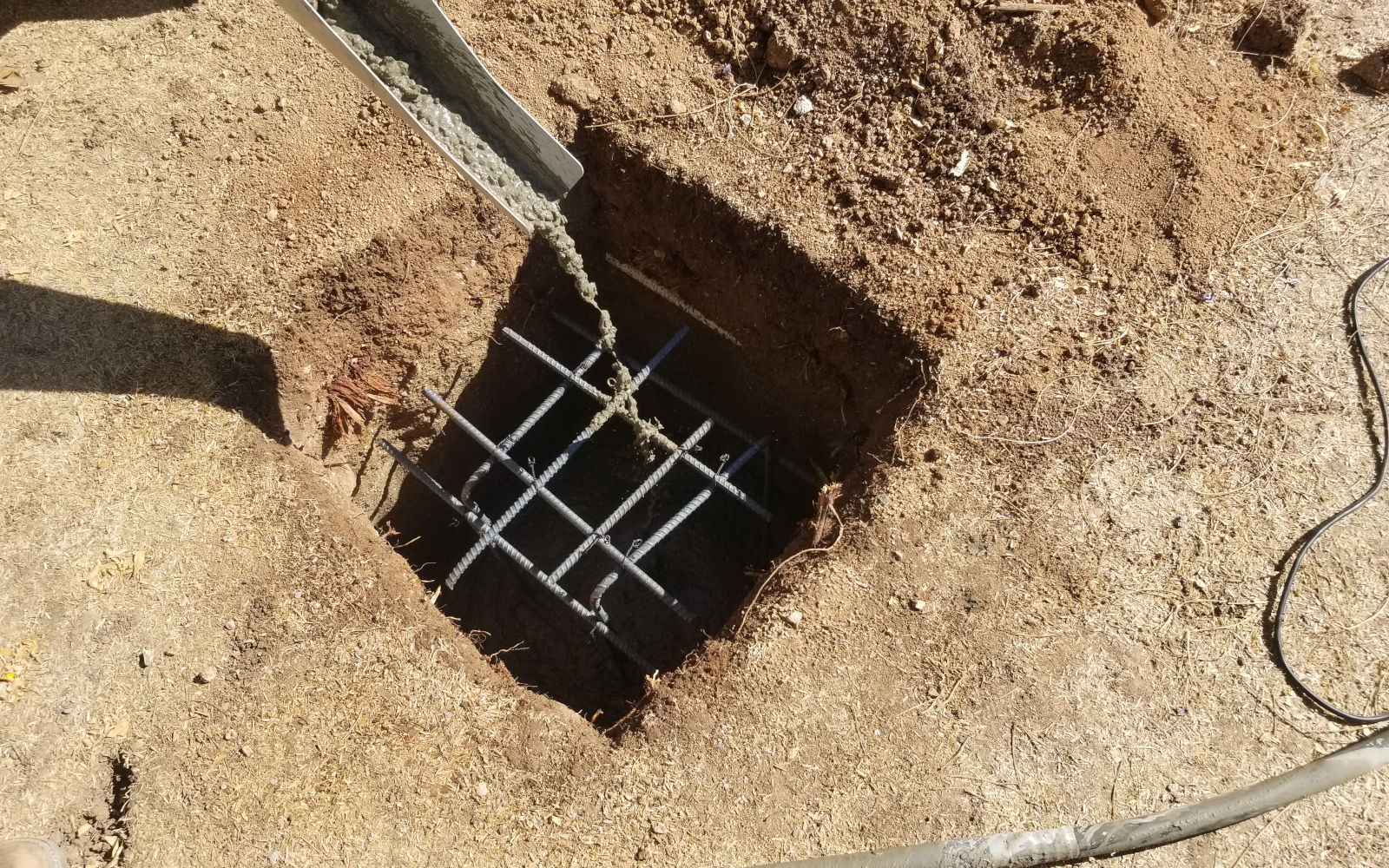 Concrete being placed around reinforcement in a pergola footing excavation in Scottsdale.