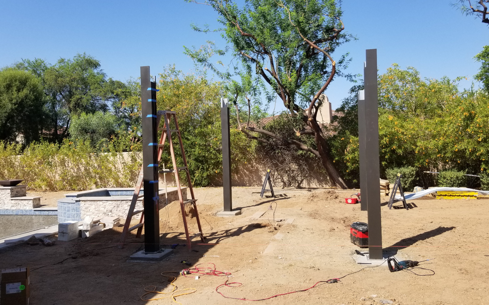 Pergola posts being installed beside a Scottsdale backyard pool