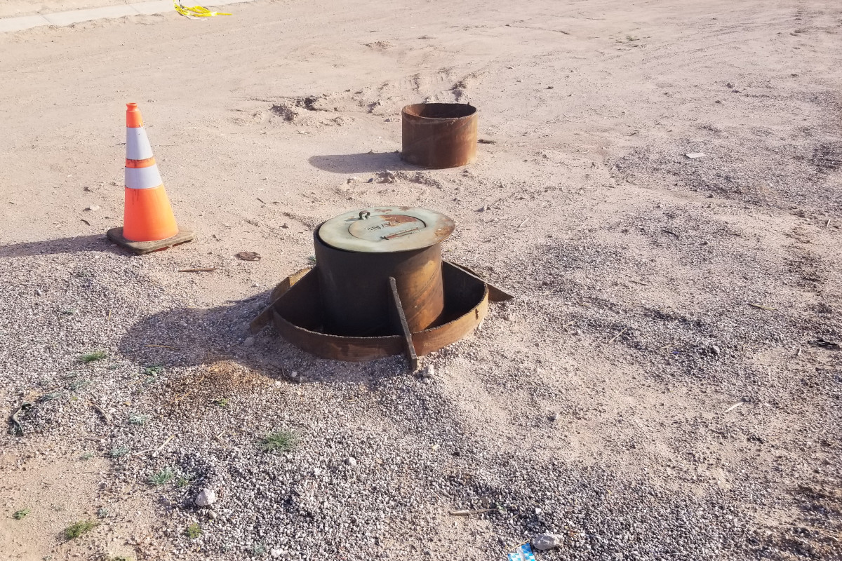 A Layne Drilling well head sticking out of the dirt ground.