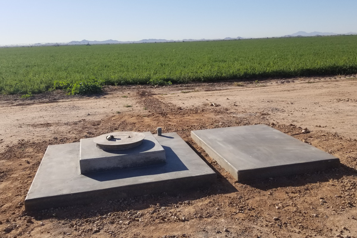 Completed concrete job for a well head, a water resource for the crops in the background.