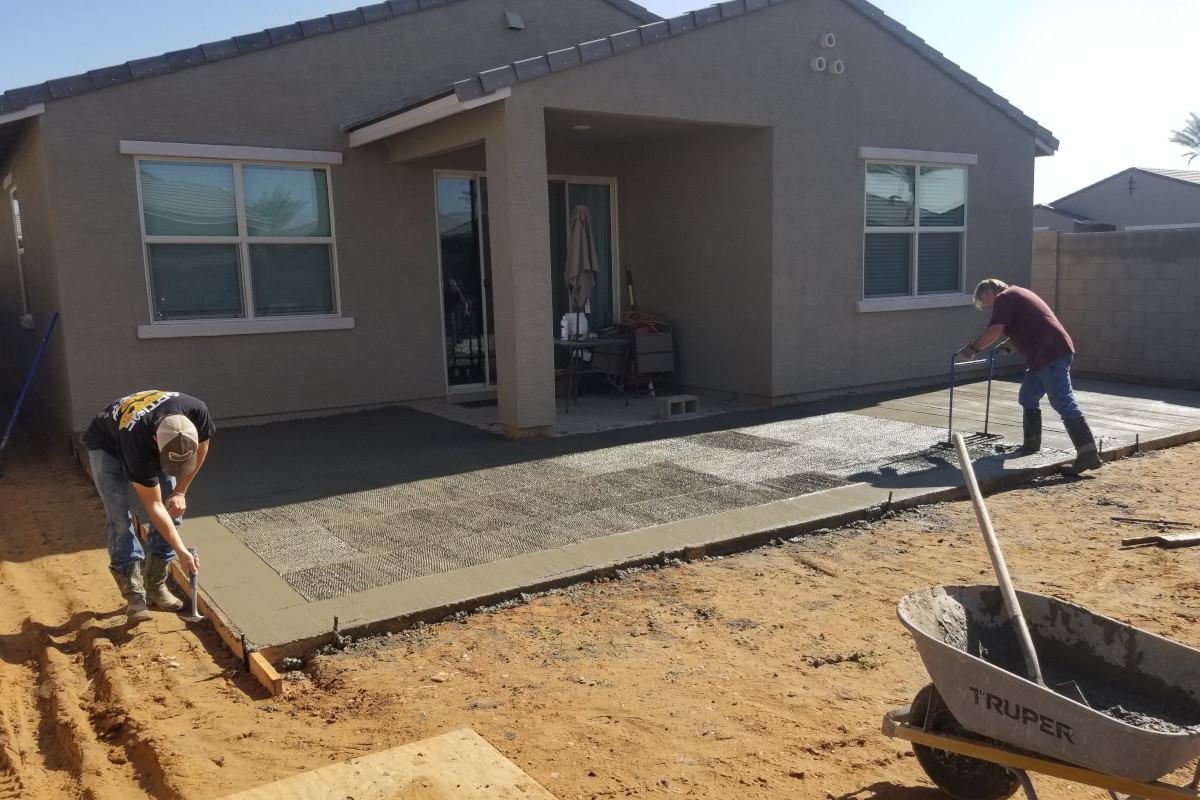 Crew placing and finishing a fresh concrete patio pour.